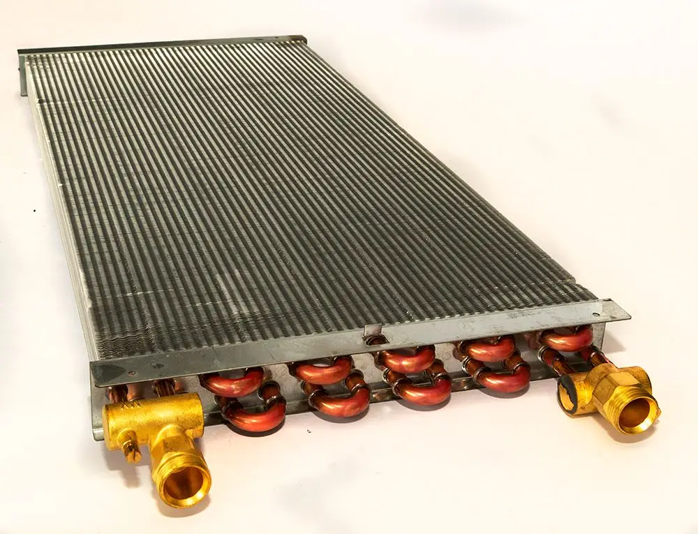 Daikin Wärmetauscher mit gerillter Oberfläche und mehreren Anschlüssen, geeignet für Heizungsanwendungen. Sichtbare Kupferrohre und Anschlussstücke aus Messing.